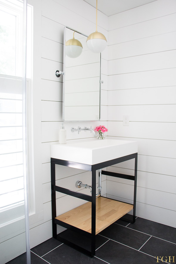 White modern bathroom makeover featuring a steel vanity, wall mounted faucet, trough sink and shiplap