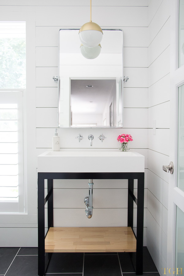 White modern bathroom makeover with a custom steel bathroom vanity, brass pendant, and shiplap