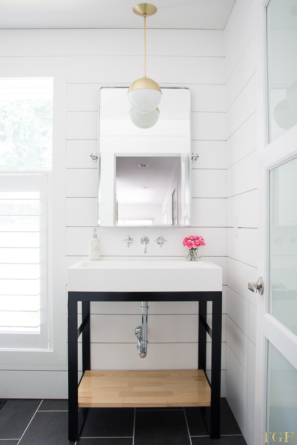 White modern bathroom makeover with a wall mounted faucet, steel vanity, trough sink and shiplap